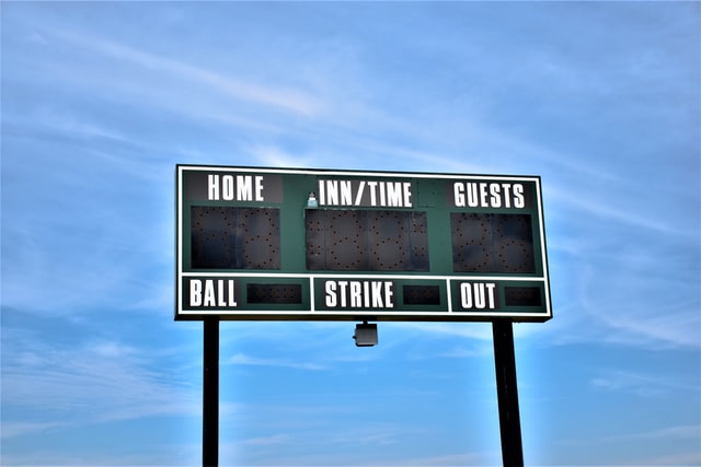 An image of a baseball scoreboard. The sign is not illuminated, but the sections for the scores for the home and guest teams, as well as for the current number of balls, strikes, and outs are all labeled.