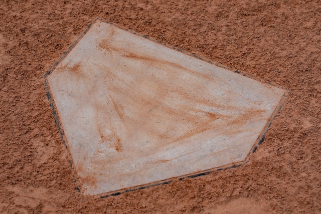 A photograph of a home plate surrounded by orange dirt.
